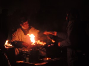 A Bolivian woman sells street food at 5am in the dark, cold streets of Tiwanaku.